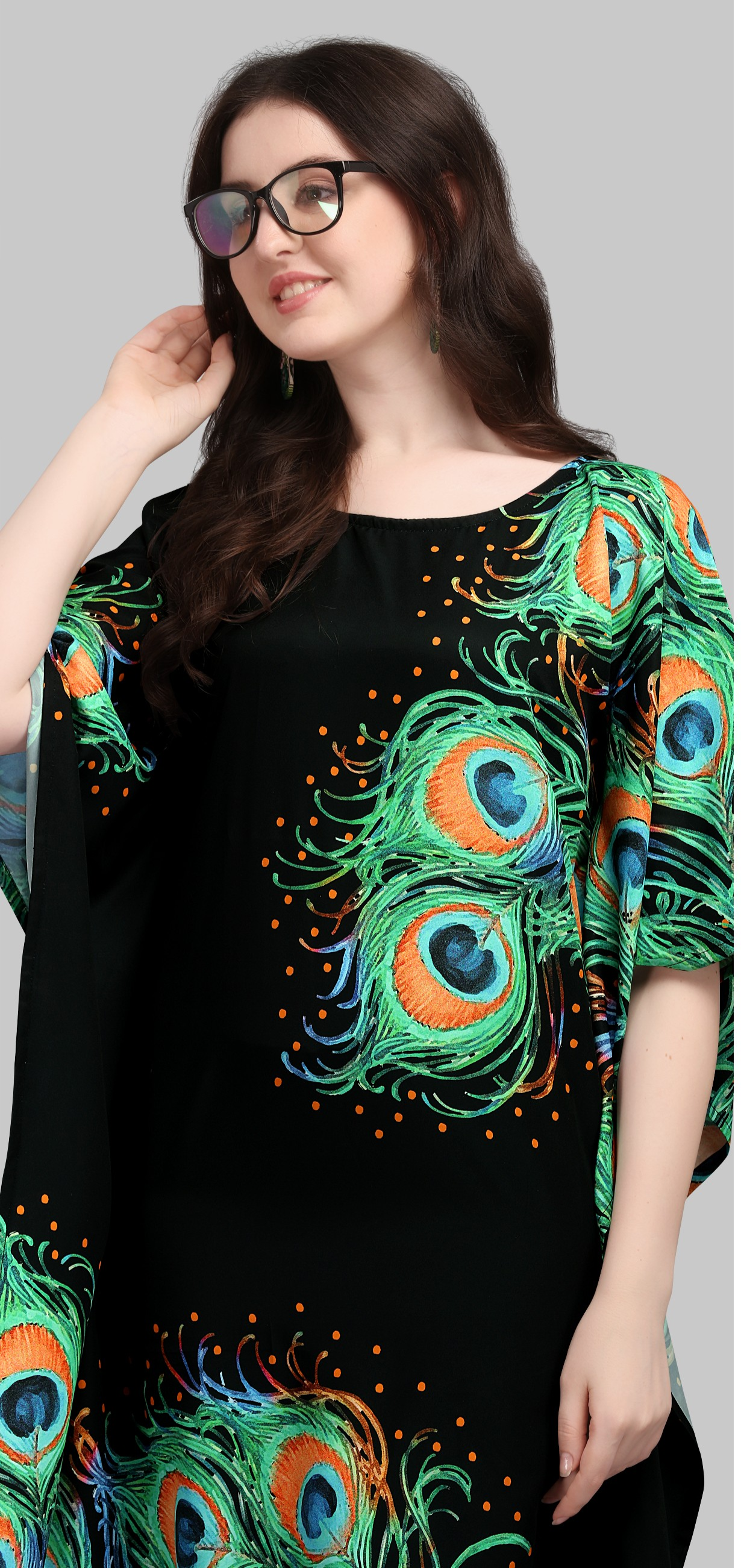 Woman wearing a black top with peacock feather design on a gray background